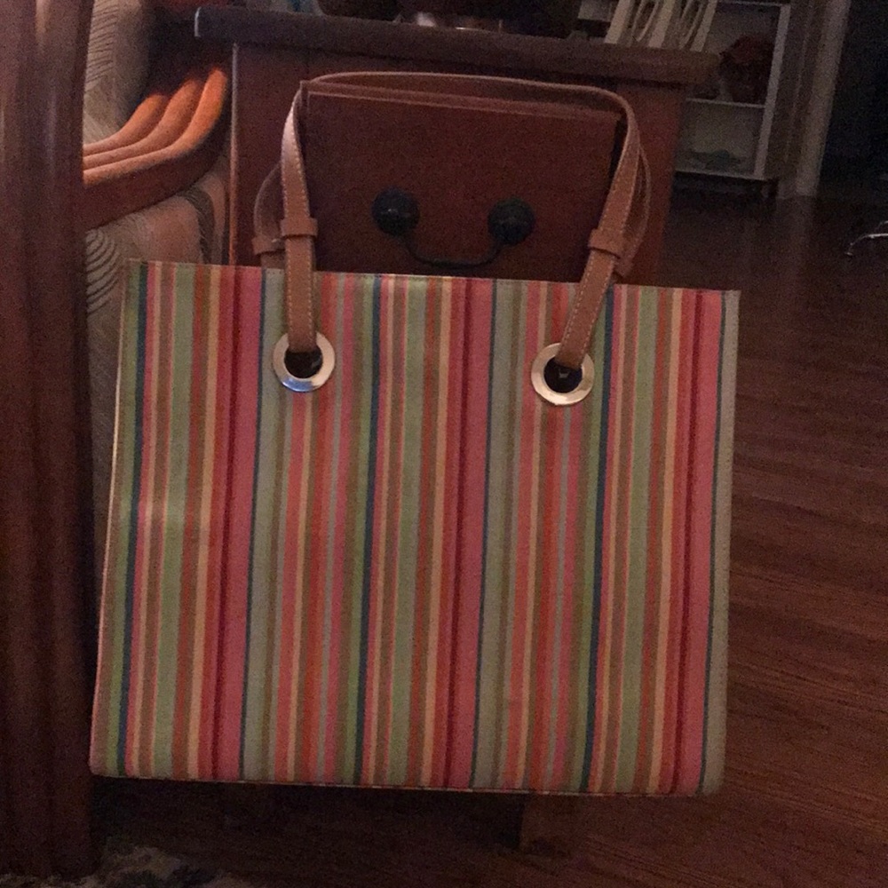 Multi colored striped shoulder bag w/grommets holding tan leather straps